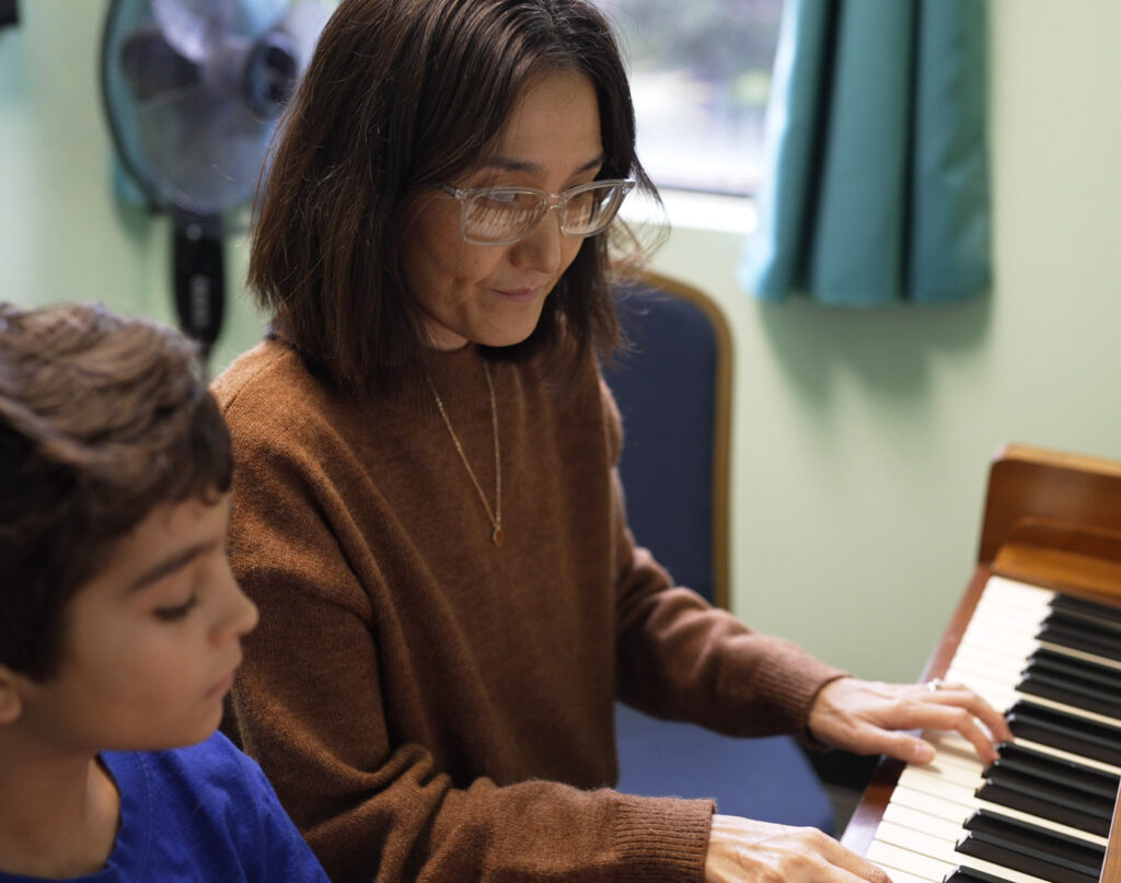 Piano teacher Eunju DeLura instructing young student in piano lesson.
